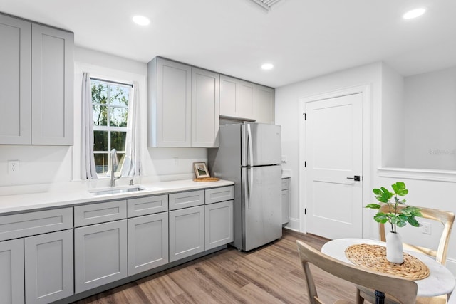 kitchen featuring gray cabinetry, sink, light hardwood / wood-style floors, and stainless steel refrigerator