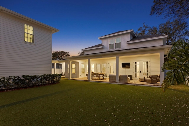 rear view of property with an outdoor living space, a lawn, a patio area, and french doors