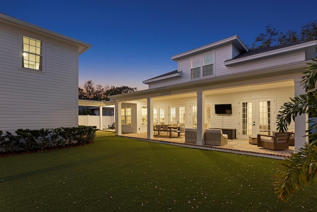 rear view of house with a patio, outdoor lounge area, a lawn, and french doors