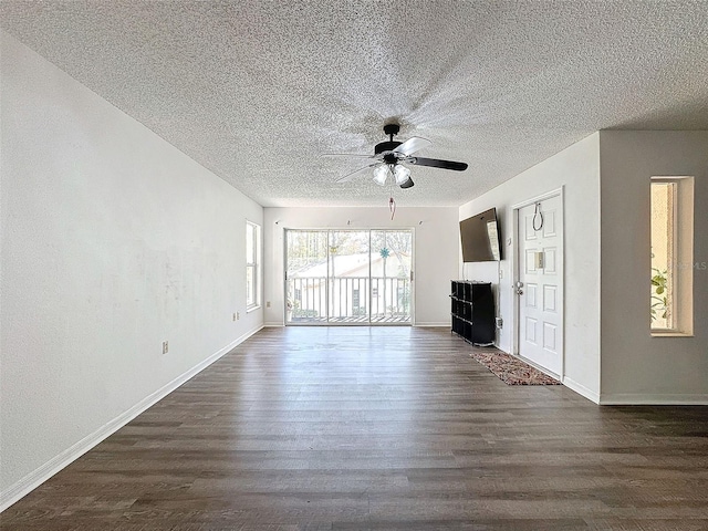 unfurnished living room featuring dark wood-type flooring and ceiling fan