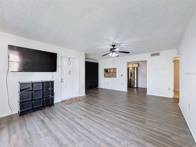 unfurnished living room featuring wood-type flooring, a textured ceiling, and ceiling fan