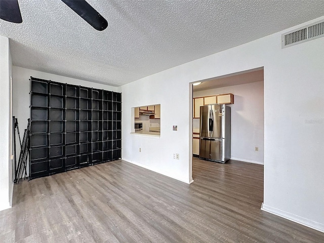 unfurnished room with ceiling fan, hardwood / wood-style flooring, and a textured ceiling