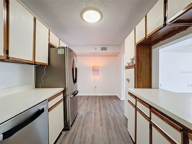 kitchen featuring dishwasher, light wood-type flooring, a textured ceiling, and white cabinets