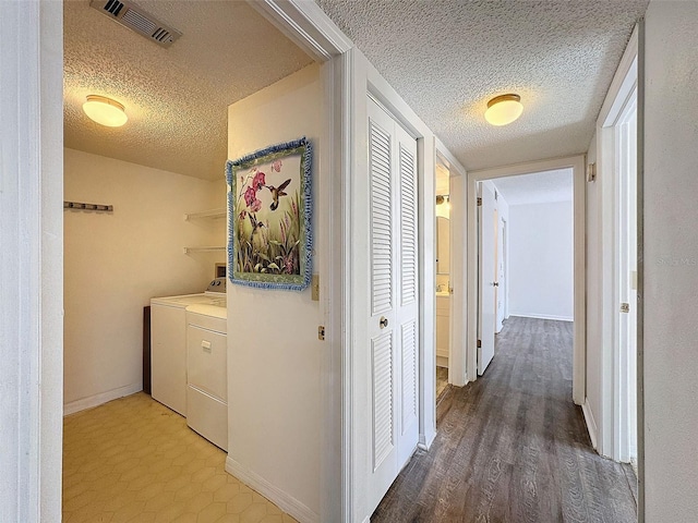 hall with washing machine and dryer, hardwood / wood-style floors, and a textured ceiling