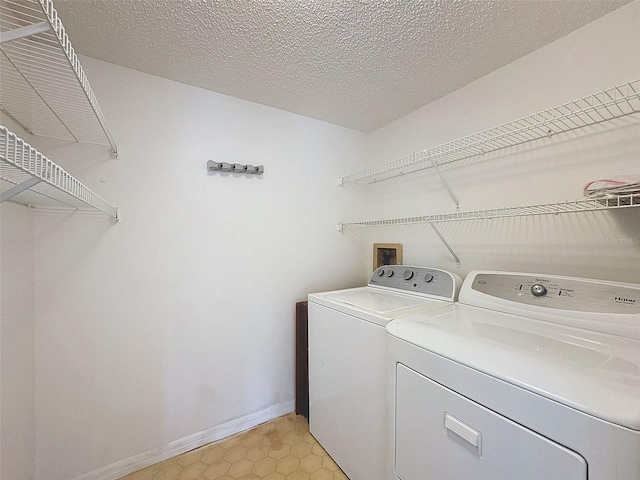 laundry area with washing machine and dryer and a textured ceiling