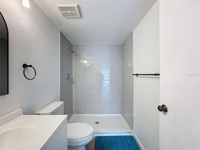 bathroom with vanity, a tile shower, and toilet