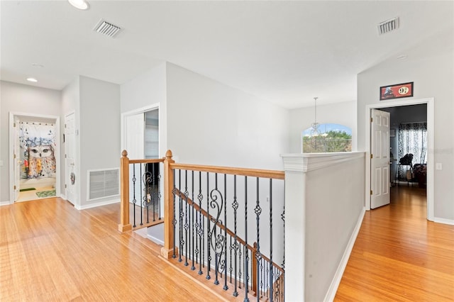 hallway featuring hardwood / wood-style flooring and a notable chandelier