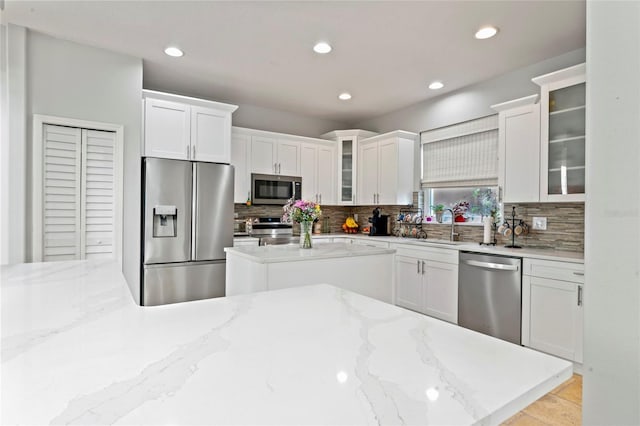 kitchen with backsplash, light stone countertops, white cabinets, and appliances with stainless steel finishes