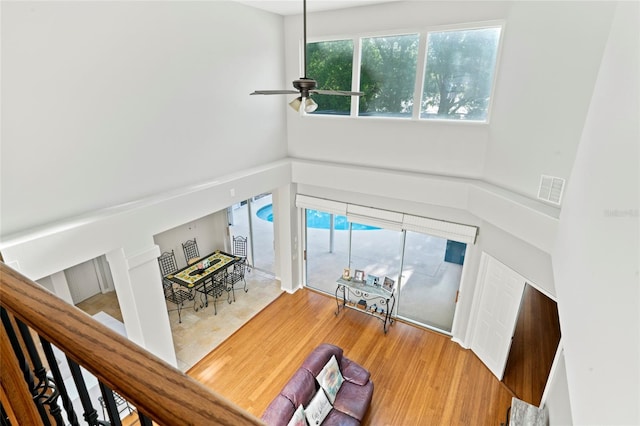 living room featuring a towering ceiling, wood-type flooring, and ceiling fan