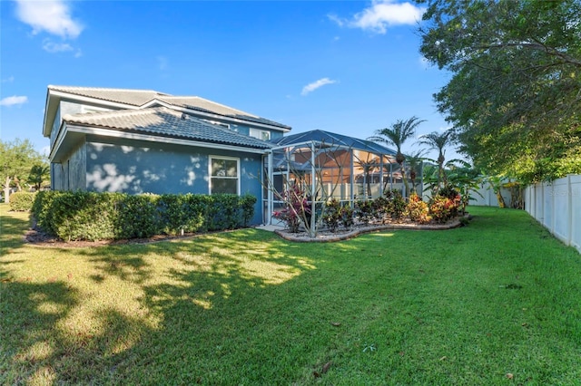 back of house featuring glass enclosure and a lawn