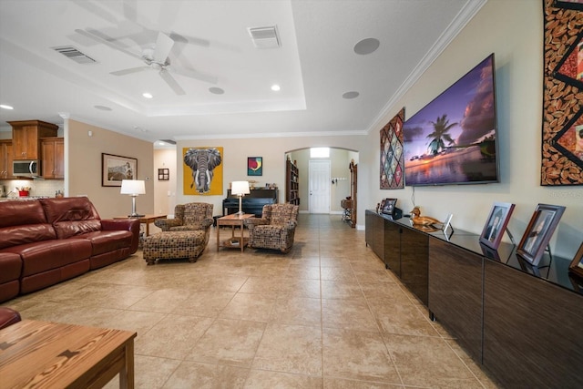 living room with a raised ceiling, crown molding, light tile patterned floors, and ceiling fan