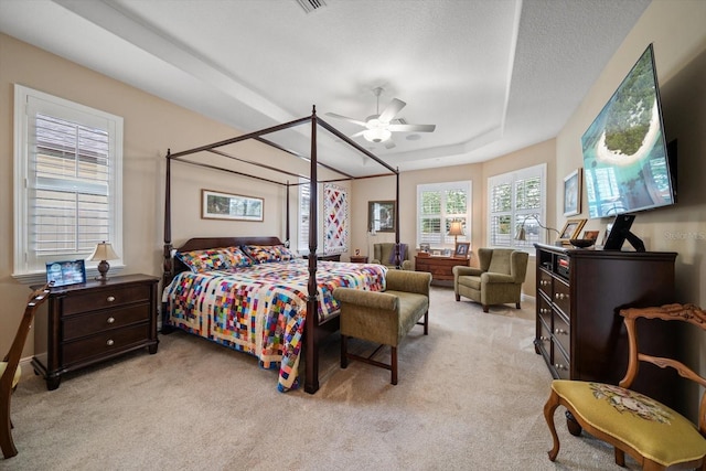 bedroom with a raised ceiling, ceiling fan, light carpet, and a textured ceiling