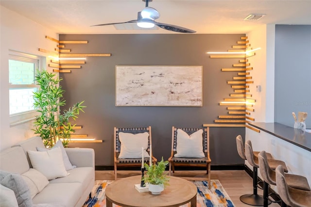 living area with ceiling fan, wood finished floors, and visible vents