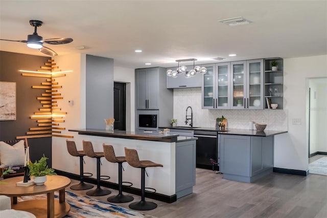 kitchen with dark countertops, visible vents, backsplash, a sink, and a kitchen bar