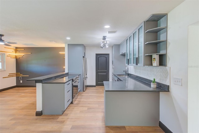 kitchen with dark countertops, freestanding refrigerator, a sink, a peninsula, and dishwashing machine