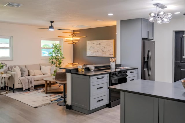 kitchen with stainless steel refrigerator with ice dispenser, dark countertops, visible vents, electric range, and a kitchen bar