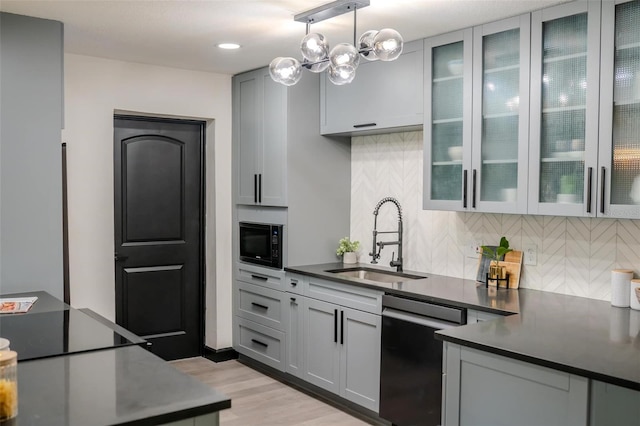 kitchen featuring dishwasher, dark countertops, gray cabinetry, black microwave, and a sink