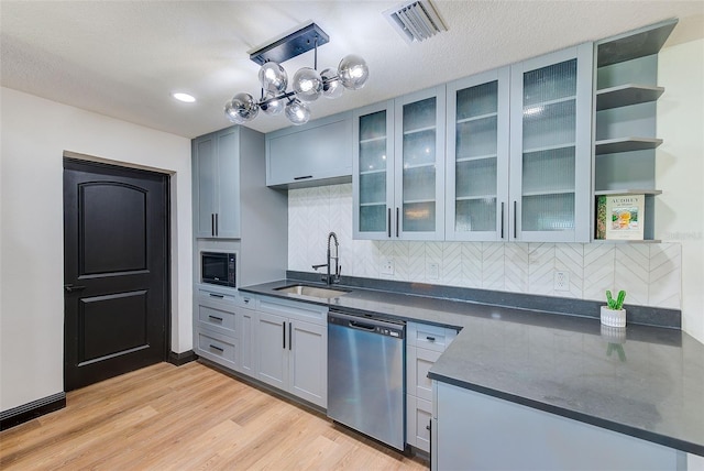 kitchen featuring visible vents, light wood-style flooring, stainless steel dishwasher, a sink, and built in microwave