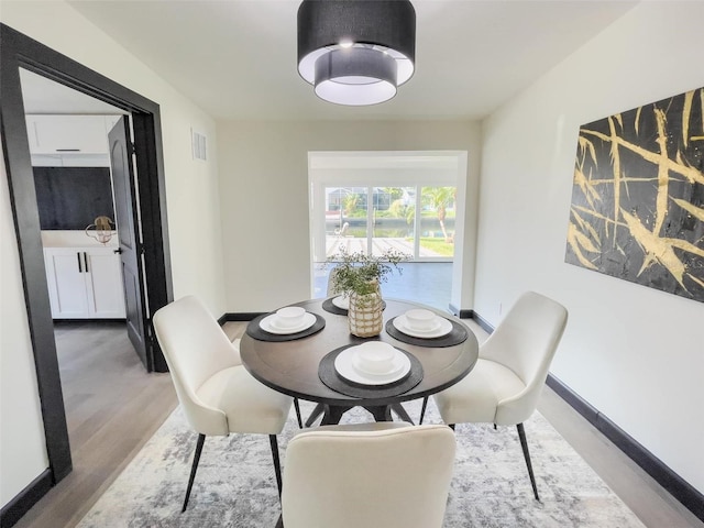 dining space with baseboards, visible vents, and wood finished floors