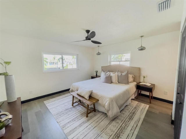 bedroom with wood finished floors, visible vents, baseboards, and multiple windows