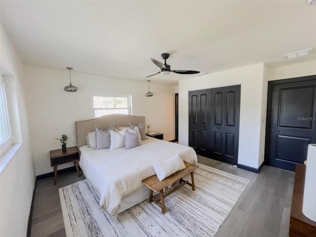 bedroom with baseboards, visible vents, a closet, and wood finished floors