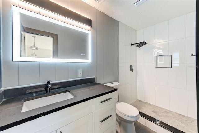 bathroom featuring visible vents, decorative backsplash, toilet, a tile shower, and tile walls