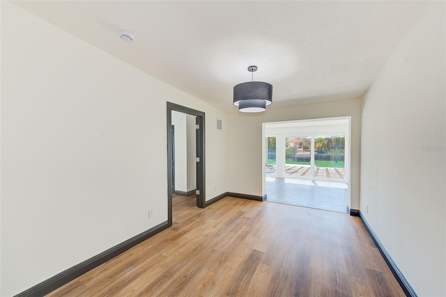 unfurnished room with light wood-style flooring, visible vents, and baseboards