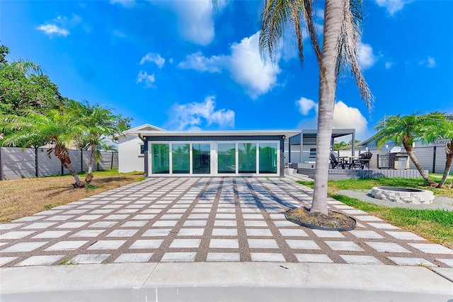 exterior space featuring decorative driveway, a patio area, fence, and a fire pit