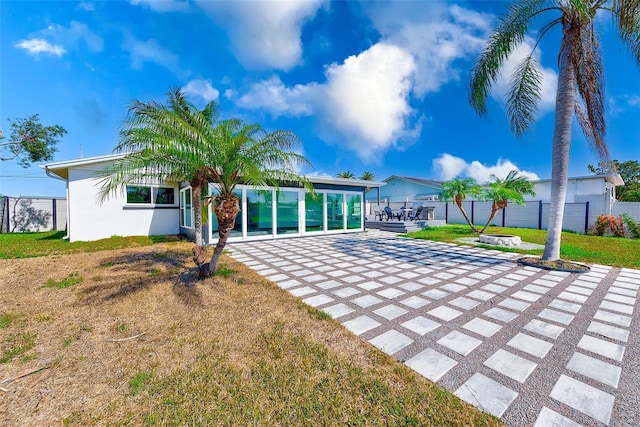 rear view of house with a patio area, fence, a lawn, and stucco siding