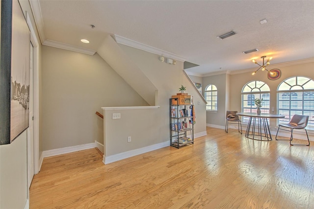 unfurnished living room featuring crown molding, a textured ceiling, a notable chandelier, and light wood-type flooring