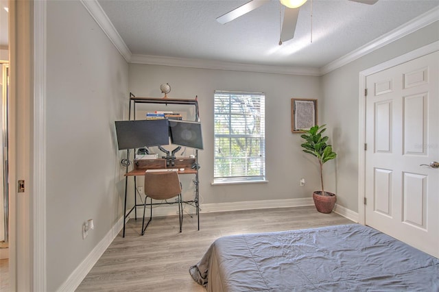 bedroom featuring ceiling fan, ornamental molding, light hardwood / wood-style flooring, and a textured ceiling