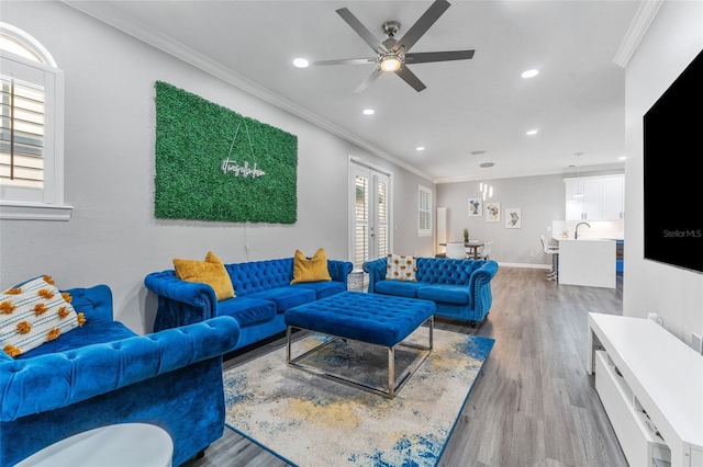 living room featuring sink, crown molding, ceiling fan, and light wood-type flooring