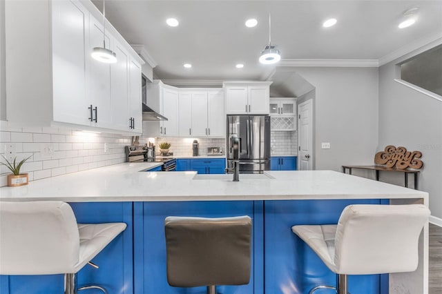 kitchen with a breakfast bar area, white cabinetry, stainless steel appliances, ornamental molding, and decorative light fixtures