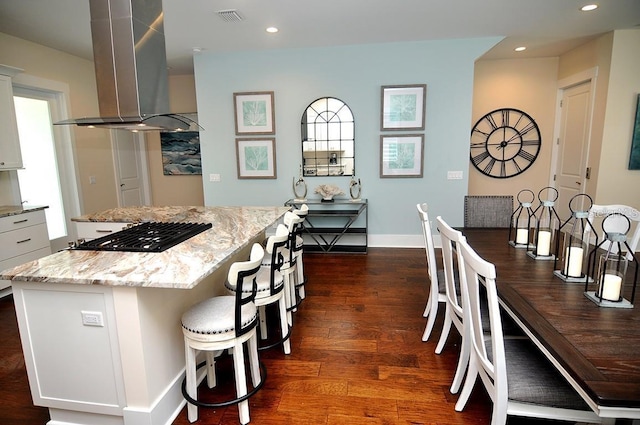 kitchen featuring a kitchen island, white cabinetry, dark hardwood / wood-style flooring, island exhaust hood, and light stone countertops