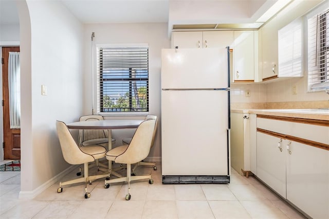 kitchen featuring light tile patterned floors, sink, white refrigerator, tasteful backsplash, and white cabinets