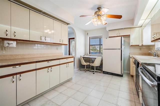 kitchen with sink, decorative backsplash, white fridge, ceiling fan, and stainless steel electric range