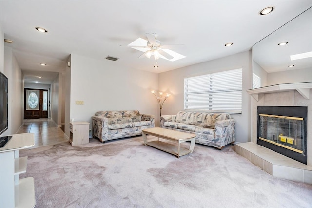 living room with a fireplace, light colored carpet, and ceiling fan