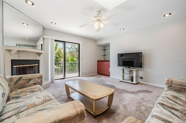 carpeted living room featuring a tiled fireplace and ceiling fan