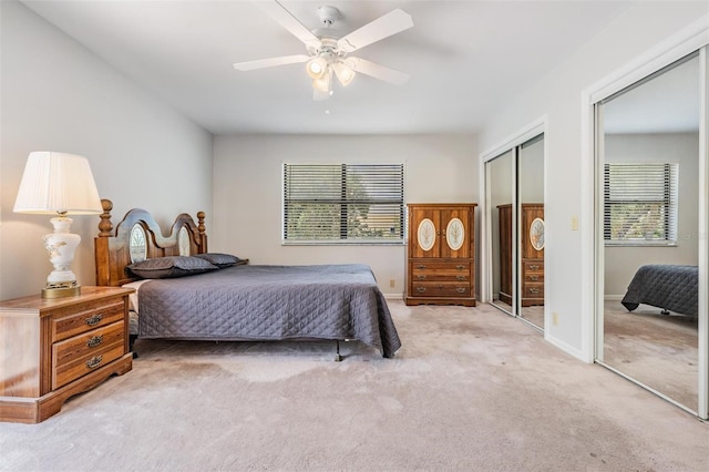 bedroom featuring multiple closets, light carpet, and ceiling fan