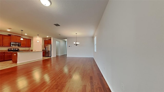 unfurnished living room with hardwood / wood-style flooring, sink, and a notable chandelier