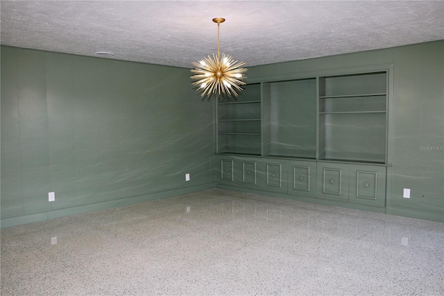 empty room featuring a notable chandelier and a textured ceiling