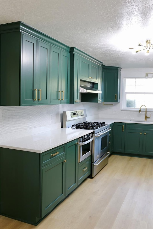 kitchen with range with two ovens, sink, a textured ceiling, and green cabinetry