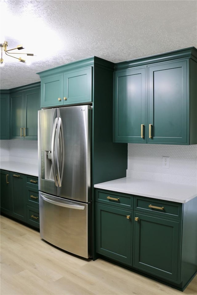 kitchen featuring green cabinetry, stainless steel refrigerator with ice dispenser, a textured ceiling, and light hardwood / wood-style flooring