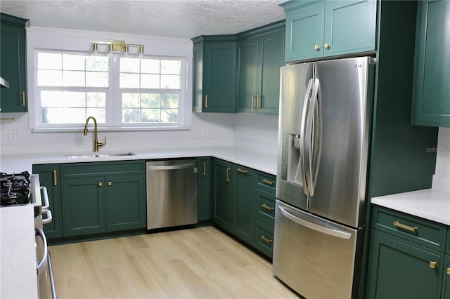 kitchen featuring sink, green cabinetry, stainless steel appliances, light hardwood / wood-style floors, and backsplash