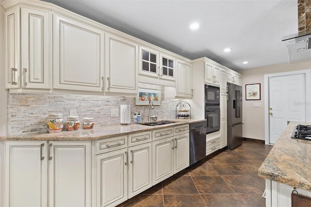 kitchen with light stone counters, sink, decorative backsplash, and black appliances