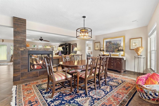 dining space with a multi sided fireplace, tile patterned floors, a textured ceiling, and a wealth of natural light