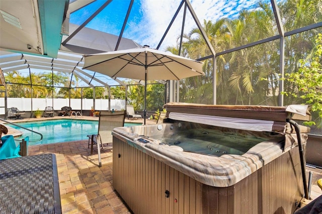 view of pool with a hot tub, a patio area, and glass enclosure