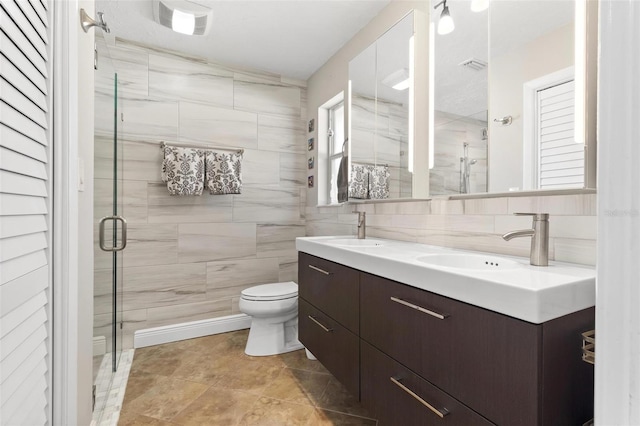 bathroom with tile walls, backsplash, vanity, toilet, and a shower with door