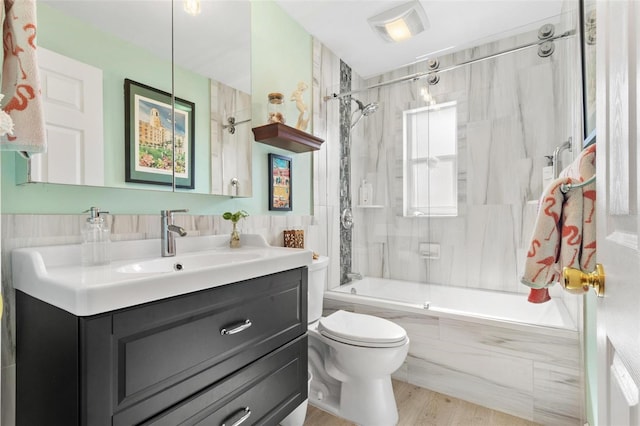 full bathroom featuring tiled shower / bath, wood-type flooring, vanity, and toilet