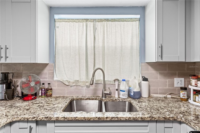 kitchen with light stone countertops, sink, decorative backsplash, and white cabinets